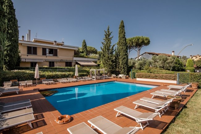 Piscina con lettini e cipressi attorno.