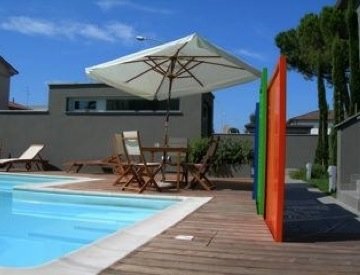 Piscina con ombrellone e tavolo in legno.