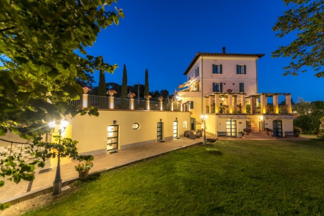 Edificio elegante illuminato di notte, circondato da un giardino.