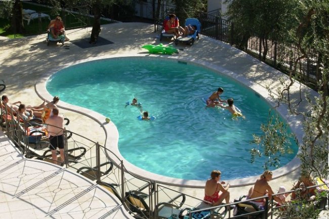 Persone rilassate attorno a una piscina.