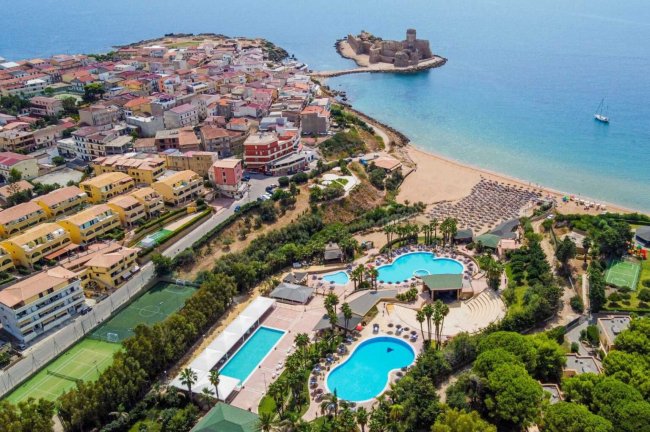Veduta aerea di un villaggio sul mare con spiagge e piscine.