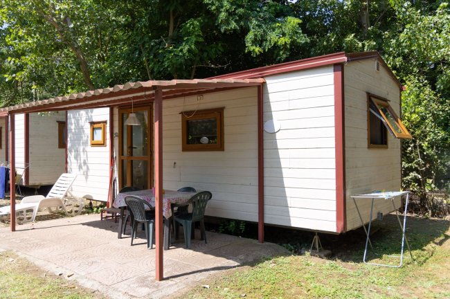 Roulotte bianca con veranda e tavolino all'aperto.