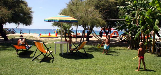 Area giardino con sedie a sdraio vicino alla spiaggia.