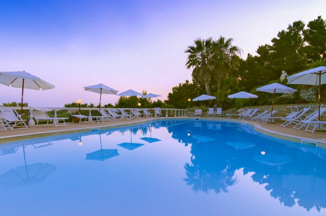 Piscina circondata da sdraio e ombrelloni.