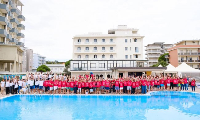 Grande gruppo di persone davanti a piscina.