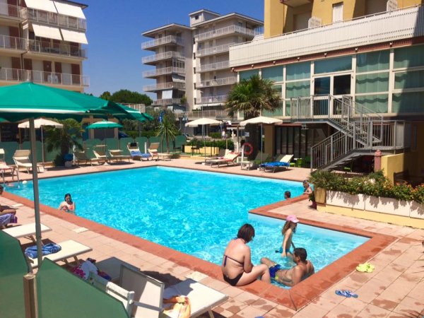 Piscina con famiglie; palazzi attorno.