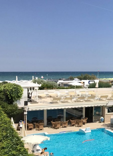Vista di un hotel con piscina e mare in lontananza.