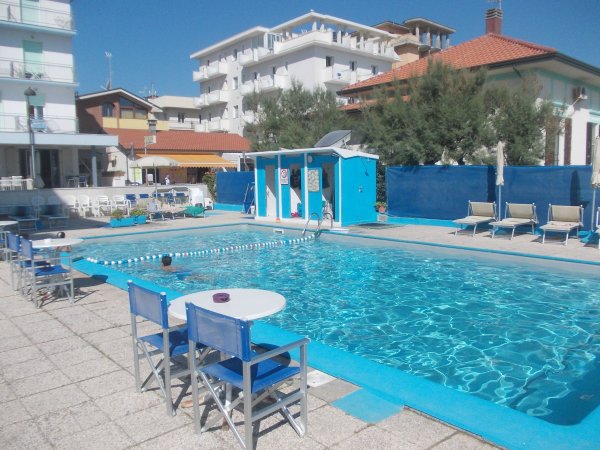 Piscina all'aperto con sedie blu e edifici.