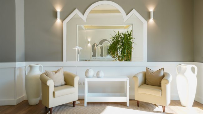 Soggiorno con specchio grande e due poltrone.