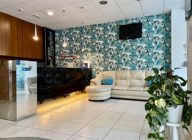 Sala d'attesa con divani e piante verdi.