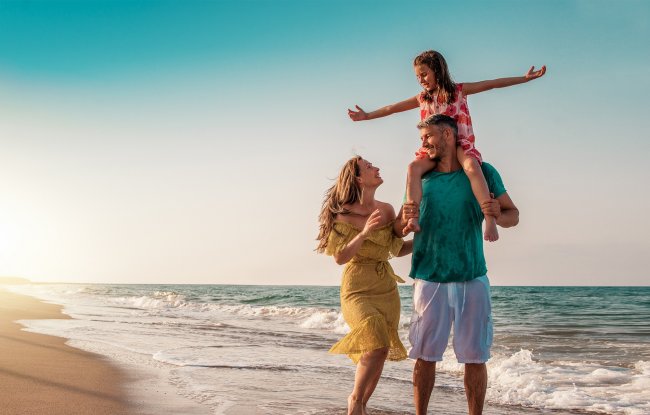 Famiglia cammina sulla spiaggia al tramonto.