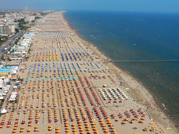 Spiaggia affollata con ombrelloni colorati e mare.