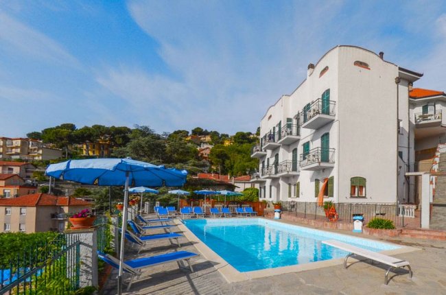 Piscina rettangolare con sedie a sdraio e ombrelloni blu.