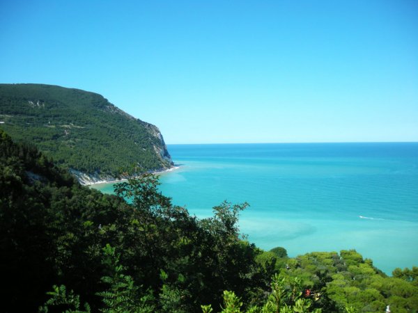 Vista costiera con mare turchese e colline verdi.