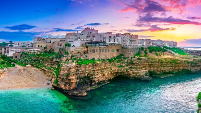 Vista panoramica di una città costiera su una scogliera al tramonto.
