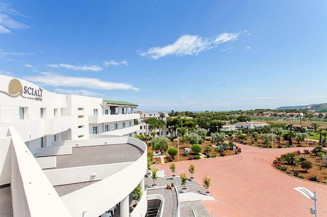 Hotel bianco con giardino e ampio cortile.
