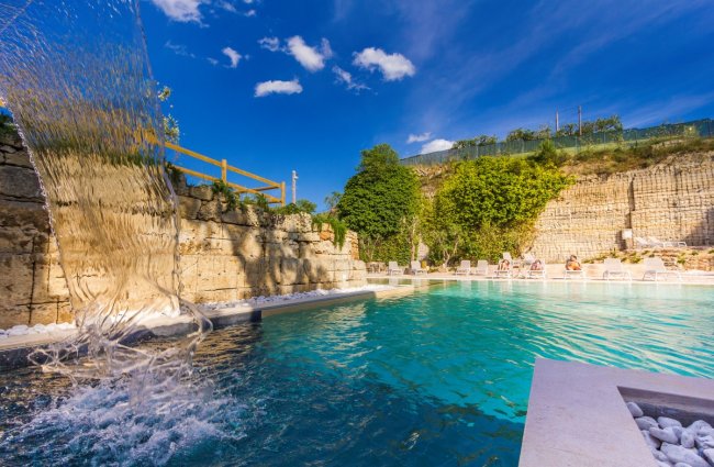 Cascata in piscina con cielo blu sullo sfondo.