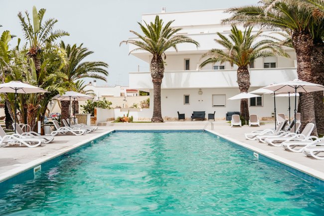 Piscina con lettini e palme.