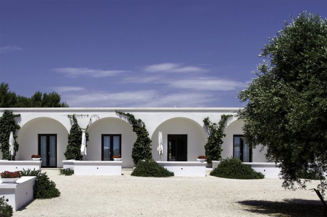 Edificio bianco con archi e piante rampicanti.