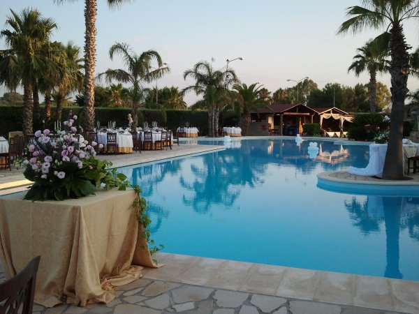 Piscina con decorazioni floreali e tavoli apparecchiati.