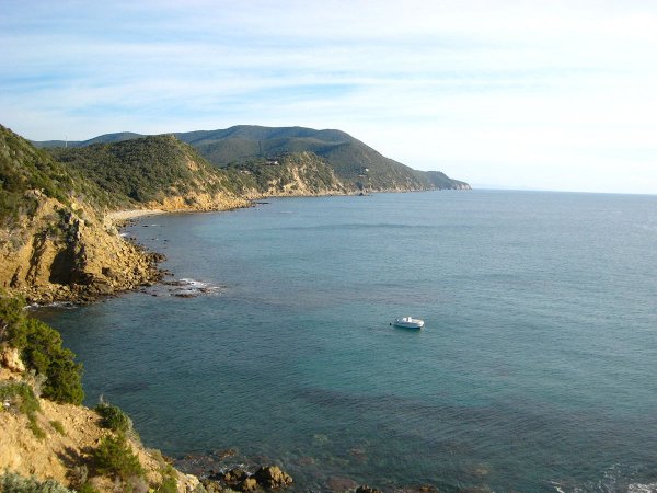 Una costa rocciosa con una barca in mare.