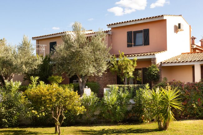 Casa mediterranea circondata da giardino verde.