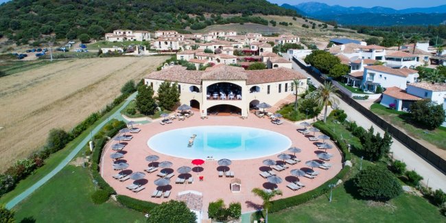Vista aerea di una piscina con ombrelloni e strutture circostanti.