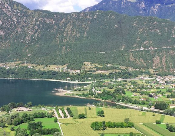 Lago e campi verdi con montagne.