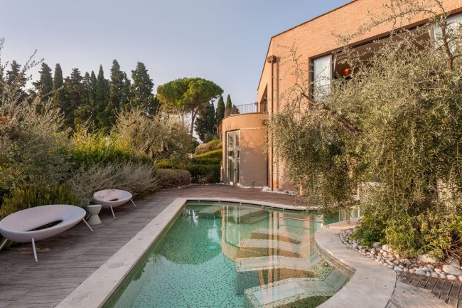 Piscina con bordo in legno e villa moderna.