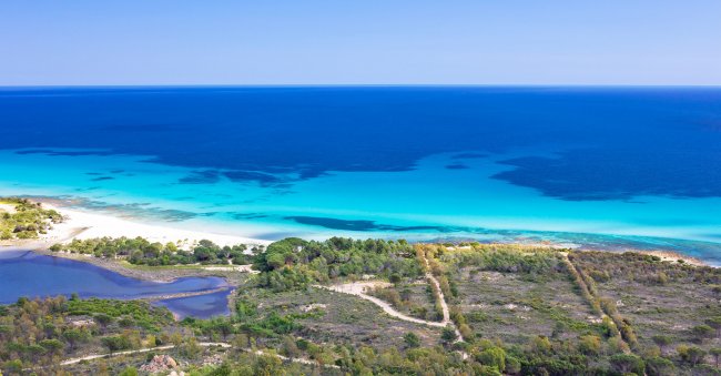 Panoramica di costa, spiaggia e mare blu.