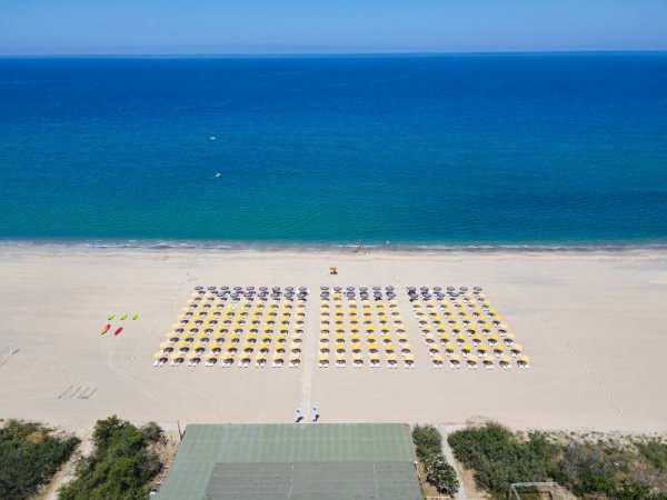 Ampia spiaggia con file di ombrelloni e mare.