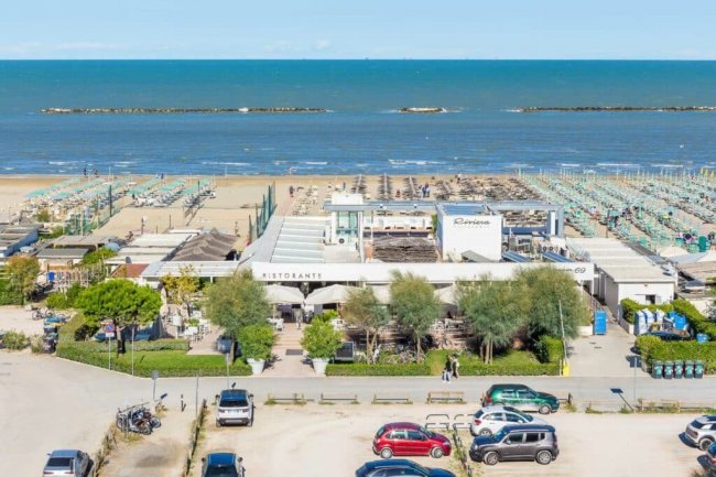 Ristorante sulla spiaggia con ombrelloni sullo sfondo.