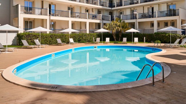 Piscina circondata da lettini e ombrelloni.