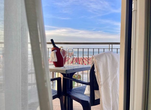 Tavolino su balcone con spumante e bicchieri, vista mare.