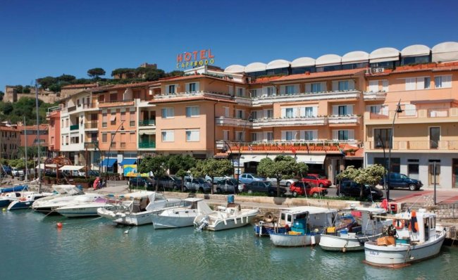 Edificio hotel fronte mare con barche attraccate.