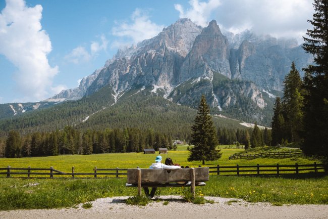 Due persone sedute su una panchina di fronte a montagne maestose.