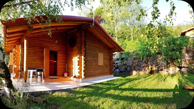Chalet in legno con giardino verde e pietre.