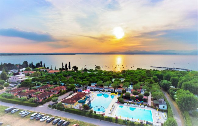 Panorama al tramonto su campeggio con piscine vicino al lago.